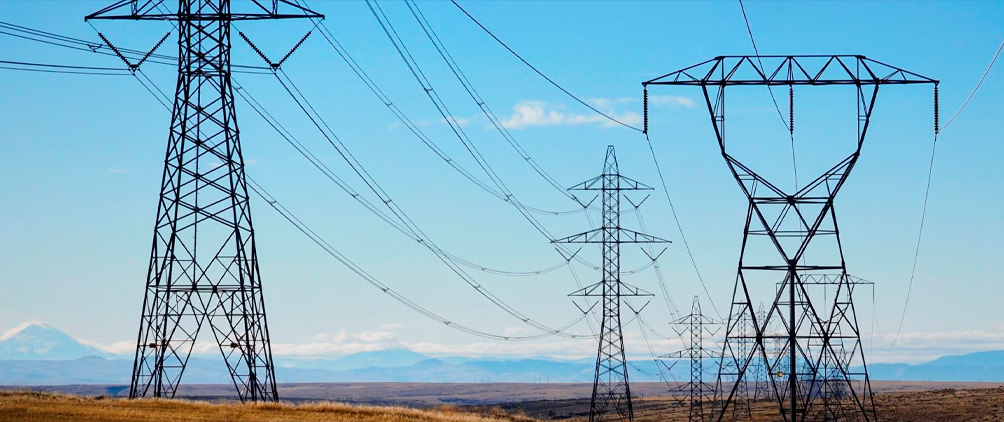 Electric transmission towers and power lines representing data infrastructure, power constraints, connectivity and AI-driven infrastructure demand.