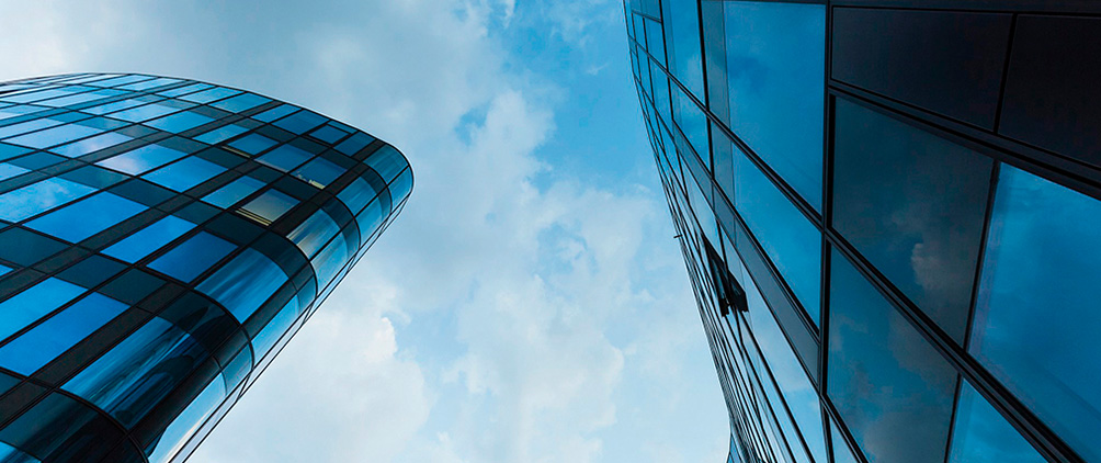 Glass office buildings viewed from below, representing real estate credit and institutional property markets.