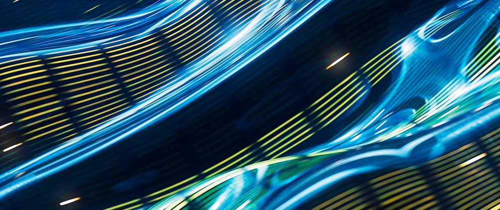 Abstract blue, green and yellow light trails representing digital infrastructure, AI investment and the AI supercycle.