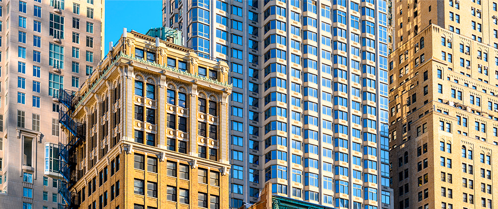 Historic and modern high-rise buildings in a city under a bright blue sky.