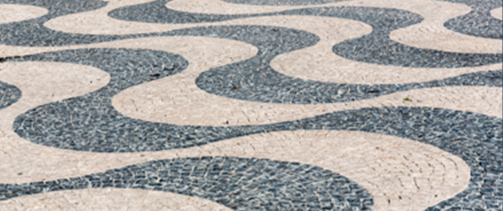 Abstract pattern of curved black and white stone paving.