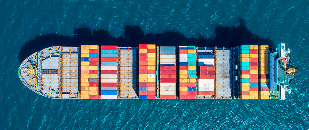 Aerial view of a cargo ship carrying colorful shipping containers across deep blue water.
