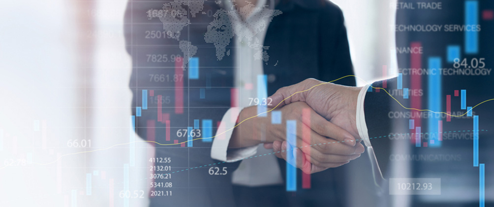 Business professionals shaking hands with stock market charts and global market data overlay.