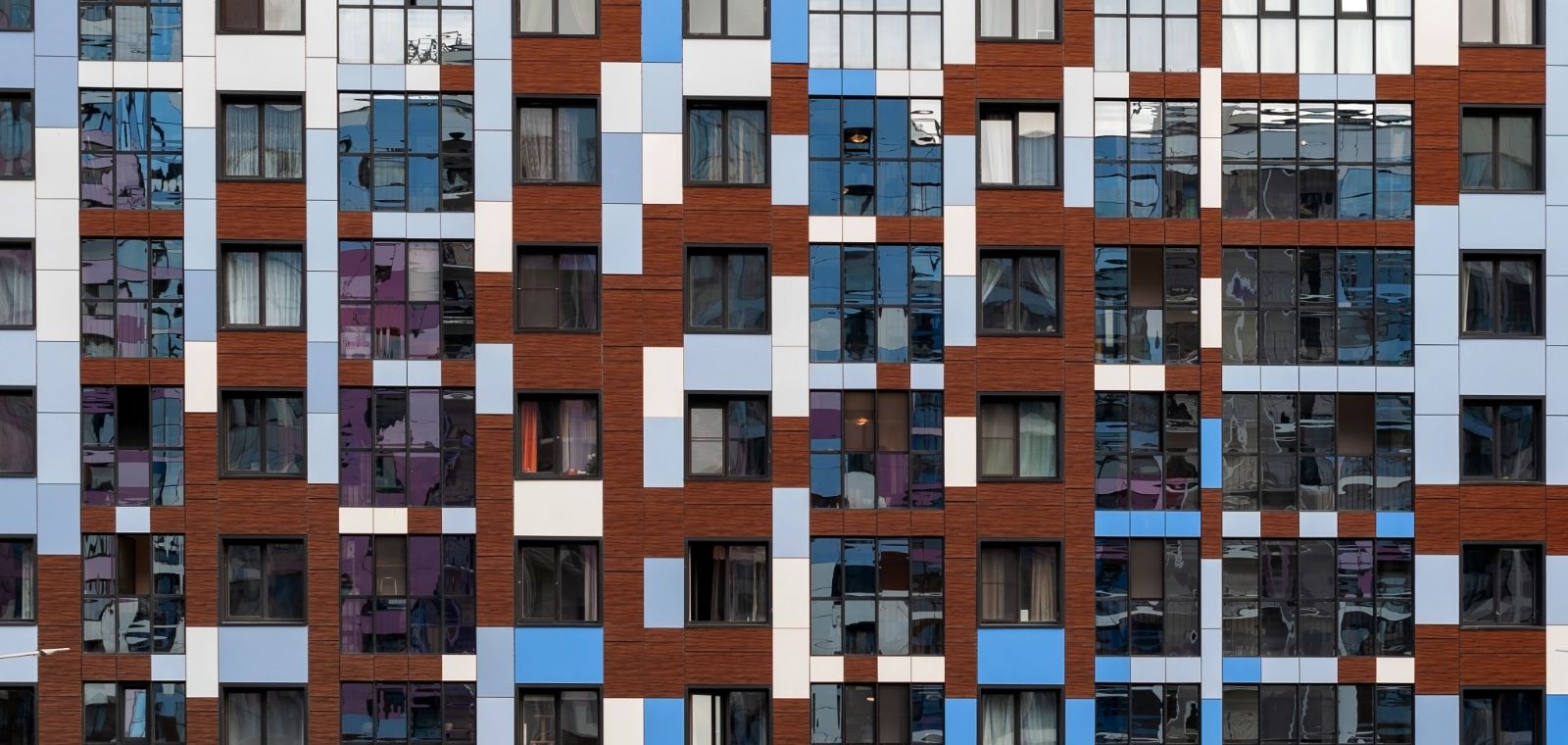 Colorful geometric windows and panels across the exterior of a modern apartment building.