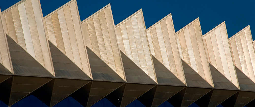 Repeating triangular architectural roof panels against a clear sky.
