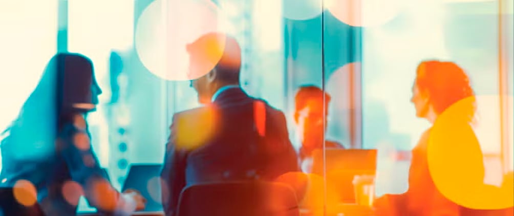 Business professionals meeting in a sunlit office with colorful reflections.