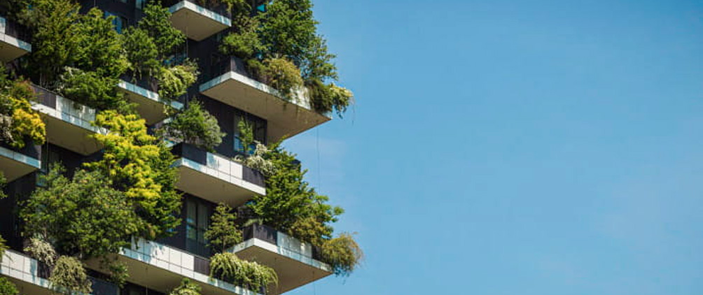 Modern building covered with trees and greenery against a blue sky.