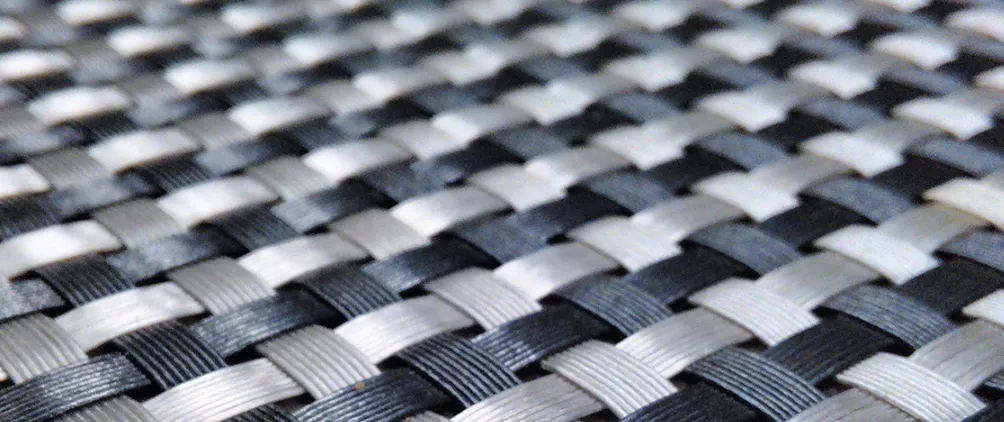 Close-up of a black and white woven pattern, resembling interlaced synthetic fibers or a basket weave.