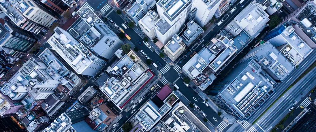 High-angle aerial view of a dense urban cityscape with tall buildings, intersecting streets, and modern infrastructure.