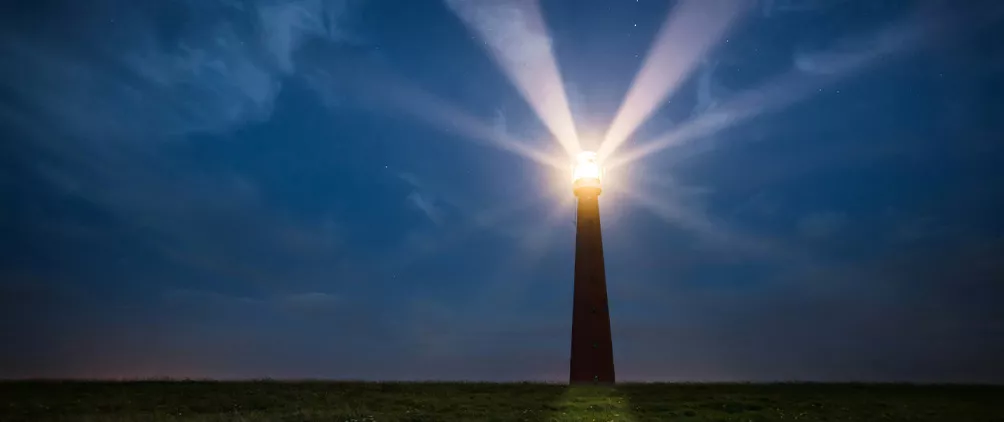 Lighthouse shining beams across a dark sky, representing bright beacons and renewed opportunities for small cap equities.