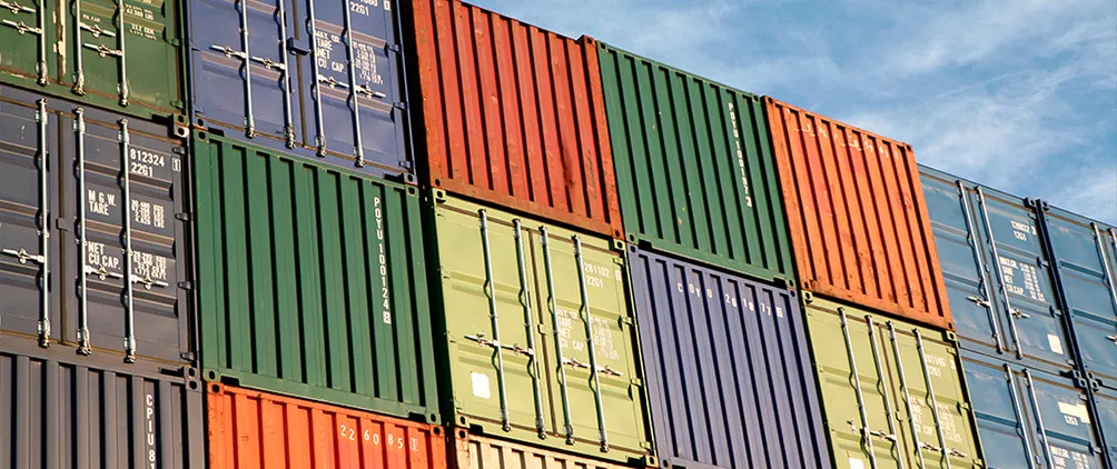Stacked shipping containers representing industrial real estate, supply chain resiliency and higher energy cost impacts on logistics demand.