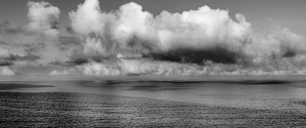 Calm ocean horizon under cloudy skies representing private credit risk, market uncertainty and financial stability.